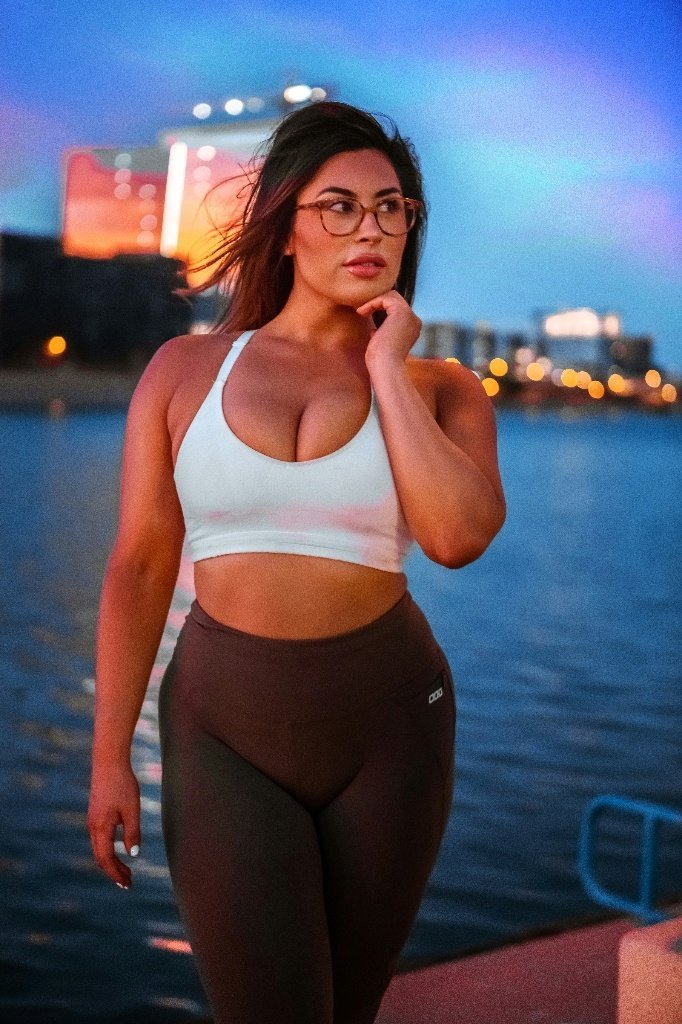 Before: Before and after AI preview of a flatter, toned stomach on a woman in a white sports bra, made in Buldy